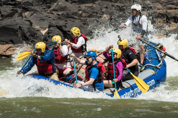 Group of solo travellers white water rafting together