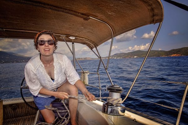 A woman pulling a rope through a winch on a sailboat